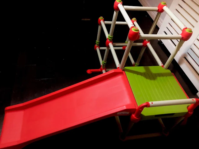 A white, green and red climbing frame with a red slide