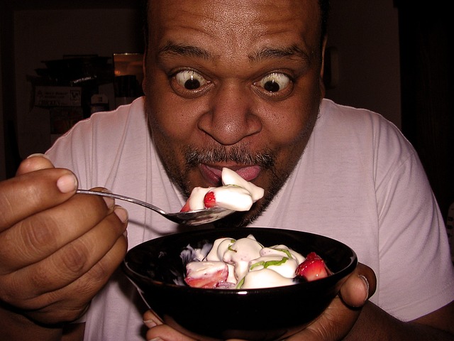 Man Hungrily Eating Yogurt and Fruit