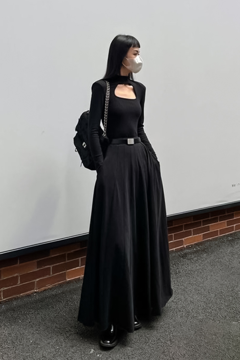 stylish young woman in total black outfit is posing for the camera on a street