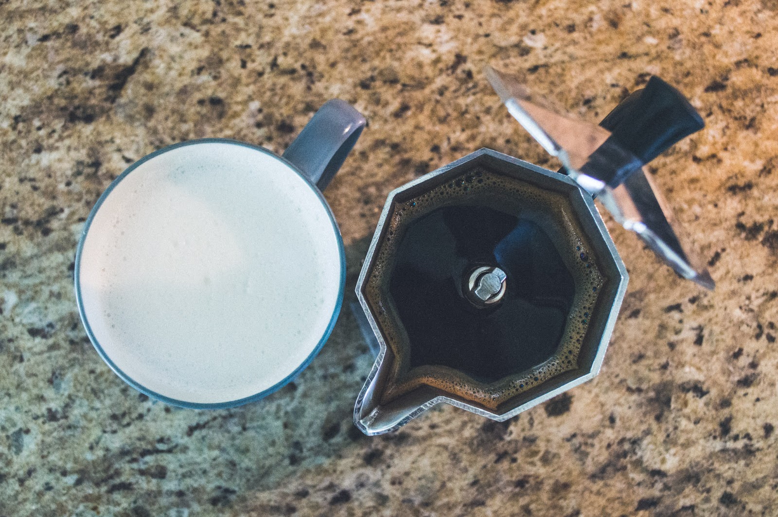 frothed almond milk in a mug and brewed coffee in moka pot