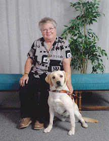 Evelyn Burris sits next to her yellow Lab Guide Dog, Colusa, on a bench