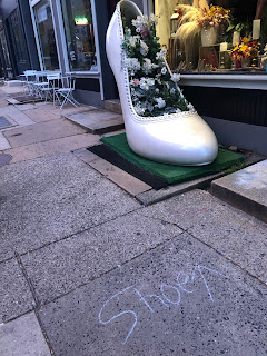 A crazy looking 6 foot high heel shoe outside a flower shop.