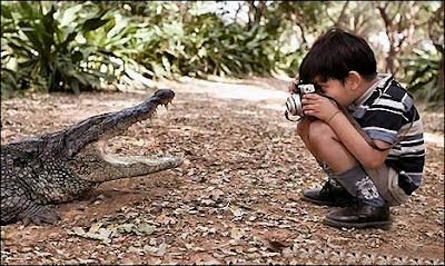 Niño tomando una foto con camara a la boca de un caiman