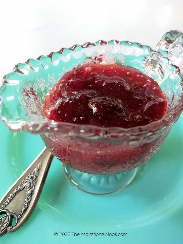 Strawberry preserve in an vintage glass bowl on a turquoise plate with a silver spoon