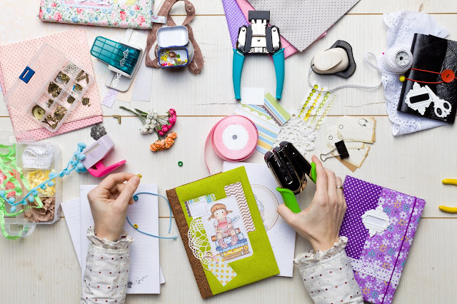 Flat lay showing different craft materials and equipment as someone sits scrapbooking