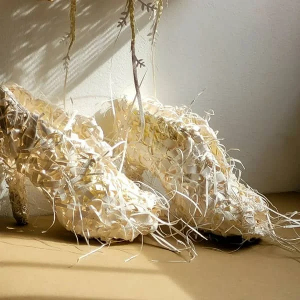 pair of off-white handmade high heel shoes composed of paper strips