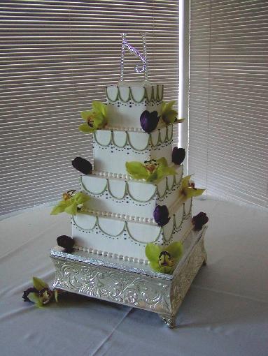White wedding cake in white with four square tiers decorated with green 