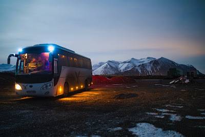 Bus with parking lights on in front of snow mountain