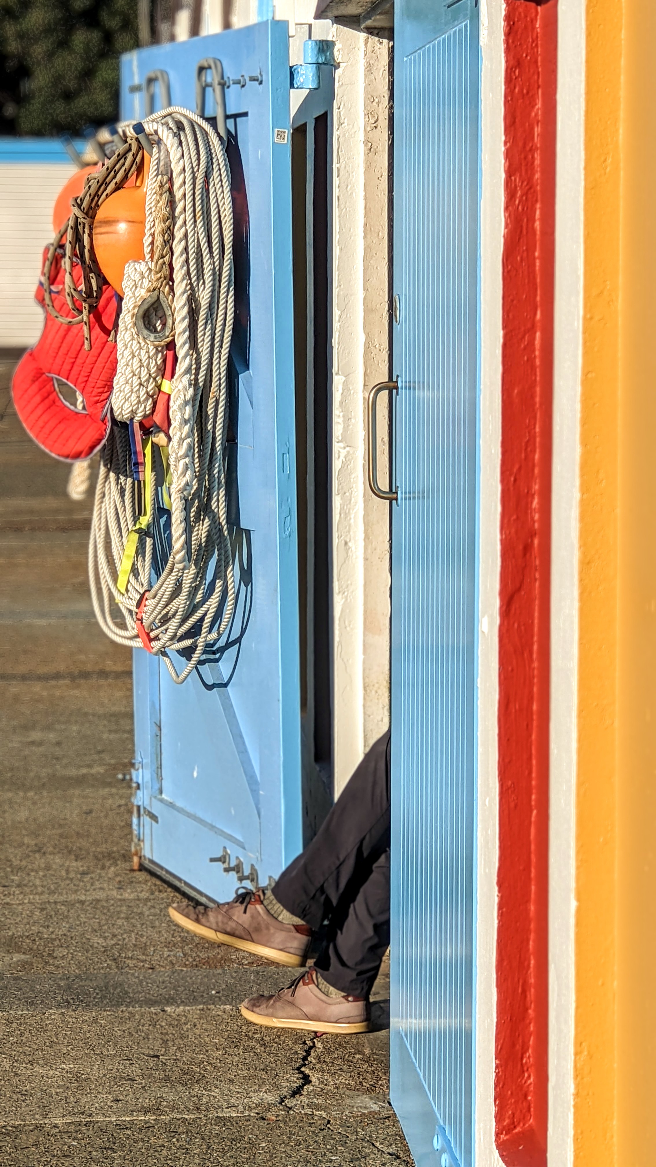 Colourful boat shed door open with feet poking out