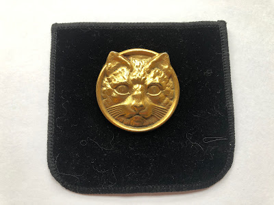 Golden cat pin of a face in a circular shape