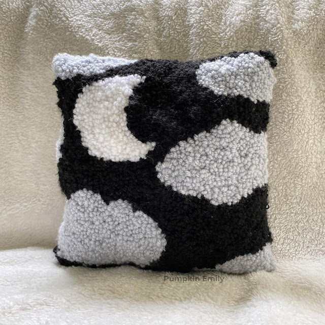 A punch needle pillow with a night sky design.