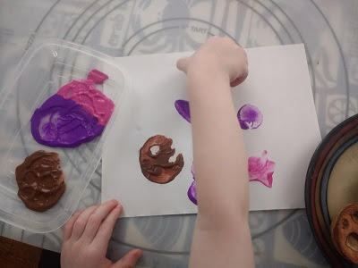 Toddler creating a space scene with potato stamps.