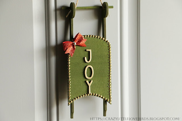 Painted green hanging sled displayed on door
