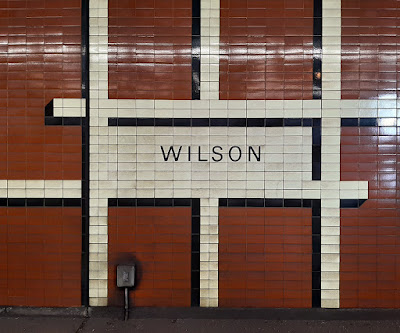 Pattern of 3D lines in tiled wall alongside the subway platform. WILSON spelled out.