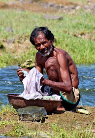 Old man washing clothes by riverside