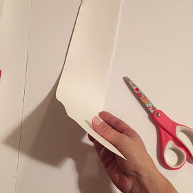 Cutting strips of white poster board with pink scissors