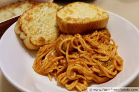 image of a shallow pasta bowl with pressure cooked spaghetti and meatballs and a side of garlic bread