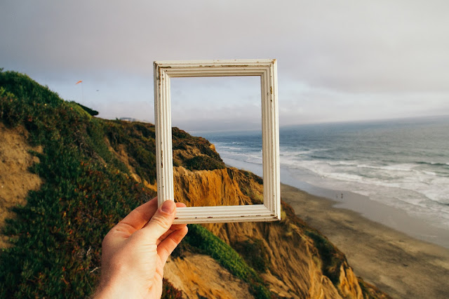 Photo by pine watt on Unsplash: Frame held up to coastal view