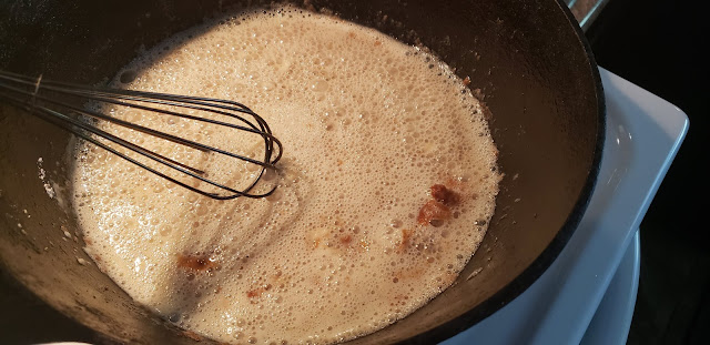 Black iron skillet whisking white gravy.