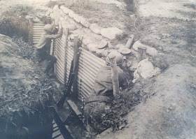 A black and white photograph of two men looking over the edge of a trench.