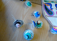 Peacock's tail eyes made from concentric circles of silver foil, plastic, milk bottle tops, buttons and beads