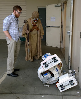 Lego Artoo crashed with bricks everywhere and wheels showing in front of a Tuskan Raider.