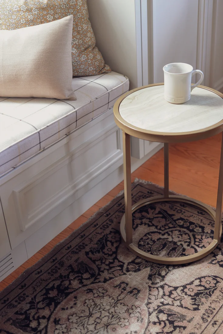 window seat with a small round side cocktail table atop a vintage rug