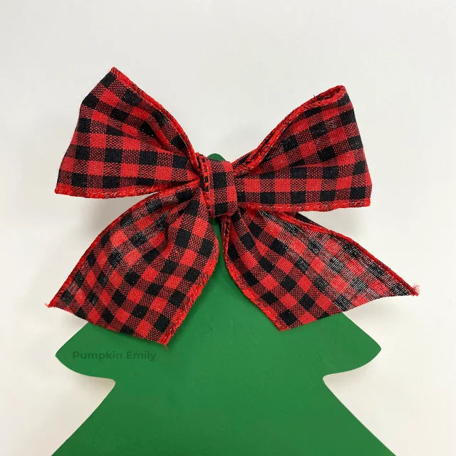 A plaid bow on a wooden Christmas tree.