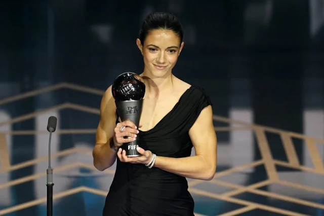 De vestido preto, Aitana sorri com o troféu do The Best na mão. Ela é morena e branca