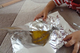 Child wrapping toys in tin foil