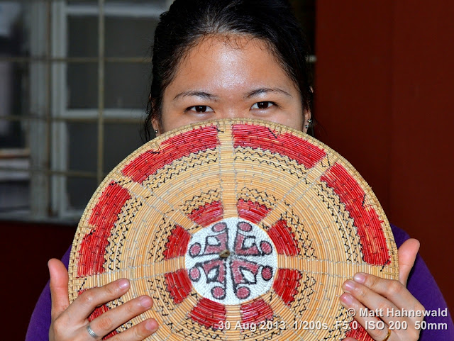 people, street portrait, headshot, face, eyes, eye contact, hiding, Malaysia, Sarawak, Kuching, Bidayuh lady, Asian conical hat