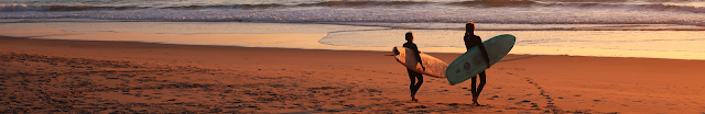 two surfers walking on beach. credit sacha verheij