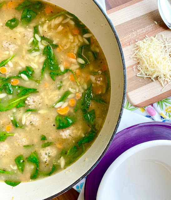 Stockpot of Italian Wedding Soup next to a white bowl