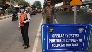 Officers stand guard at a police check point as the large-scale restriction is imposed to curb the spread of the coronavirus outbreak in Jakarta, Indonesia, Monday, Sept. 14, 2020. (AP Photo/Achmad Ibrahim)
