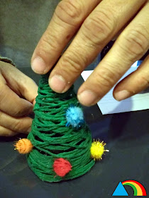 Decorando mini árbol de Navidad de lana con pompones de colores