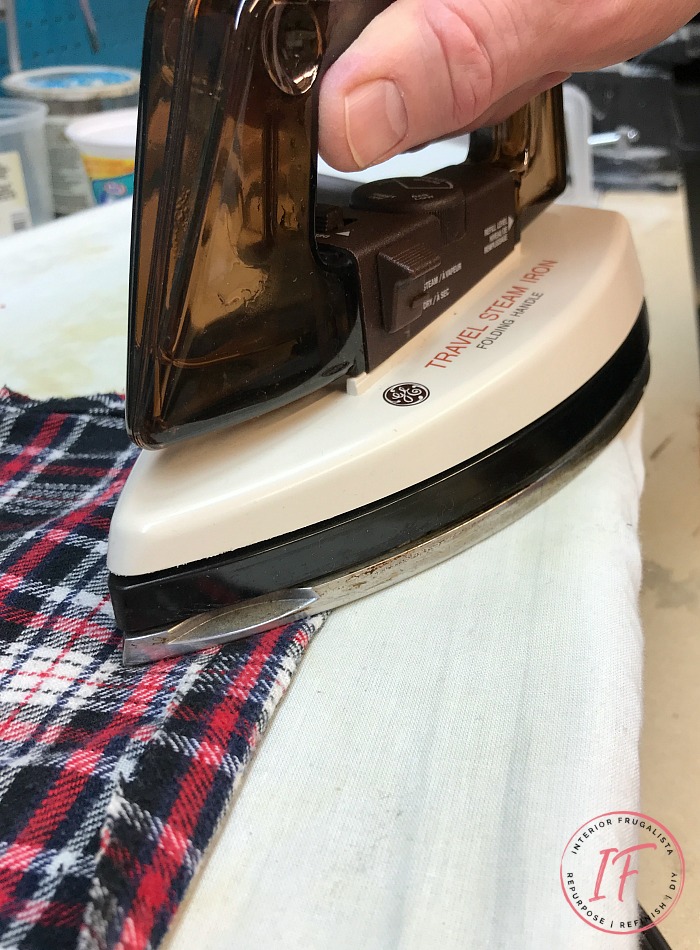 Ironing folds on a cut up flannel shirt to line a wooden Christmas box.