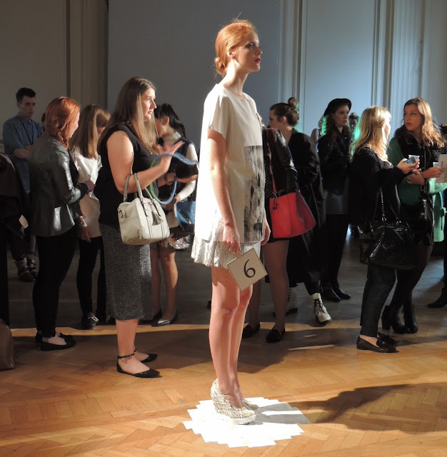 Model in white stands in front of London Fashion Week bloggers