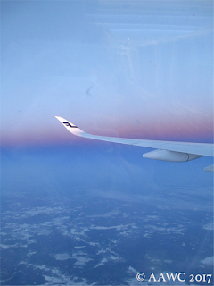 A photo taken from a plane, includes a pink/purple sunrise over Russia and a wing of the plane.