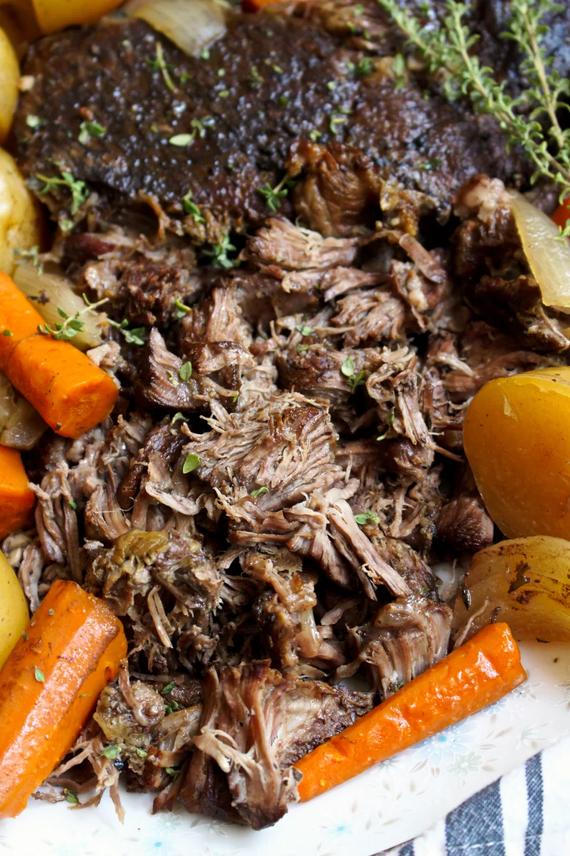 Shredded Pot Roast with cooked carrots on a white plate.