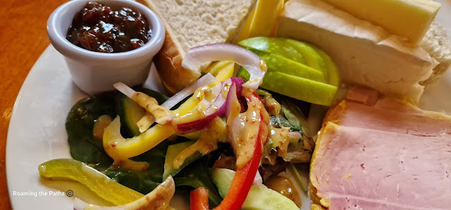 Close up of Ploughmans with Yellow Pepper, leaves and onion in mustard dressing, with Cheddar, Brie, Ham, Butter and bread forming a tasty looking backdrop.