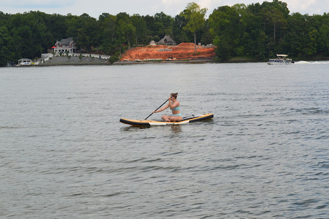 Elizabeth sitting on the paddle board paddling in the water.