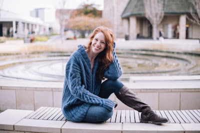 a young woman sitting on a bench in blue cable knitted cardigan