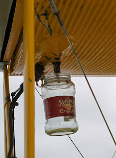A peanut butter jar, attached with wire to the fuel drain tap of a Tiger Moth