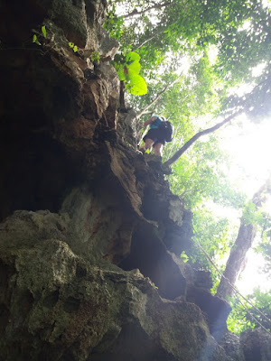 Foto van een medereiziger die buitenkant van de grot op Koh Libong beklimd