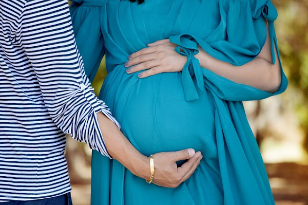 woman hand holding another woman's pregnant belly