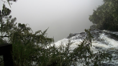 The water rushes over the edge, into the fog below.