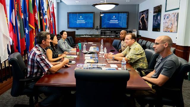 Six people in disucssion sit at a large table