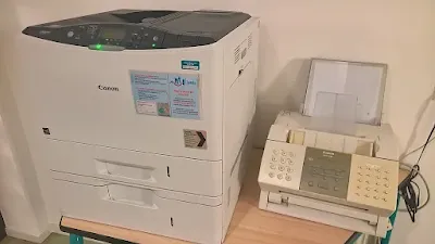 A photo of modern fax machine alongside an Xerox Machine