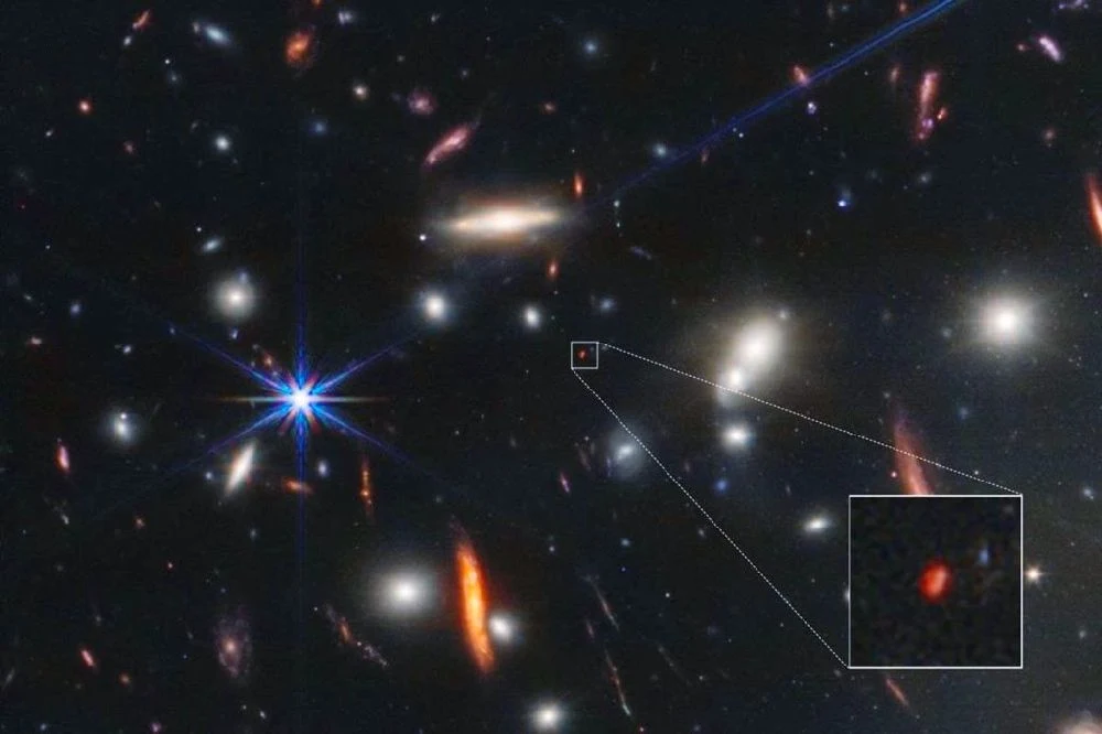 Una imagen de una Galaxia muy lejana, captada por el telescopio James Webb revela la composición química del universo primitivo. La galaxia puede verse como una "mancha" roja en el fondo de la primera imagen de campo profundo del JWST.