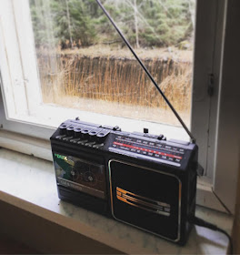 musta vanha radio ja kasettisoitin  ikkunalaudalla ikkunasta näkyy joki